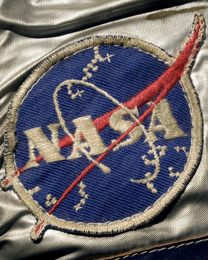 A detail of Alan Shepard's spacesuit featuring the "meatball" patch, a blue circle with the text "NASA" on it and a red swoop. 