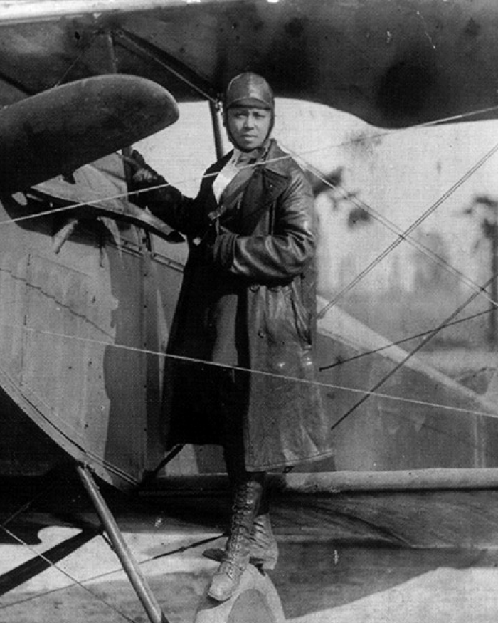 A woman stands on the wing of an airplane