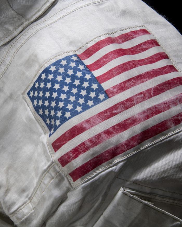 A close up of the should of Neil Armstronng's spacesuit. An American flag patch and the mission patch are visible. 
