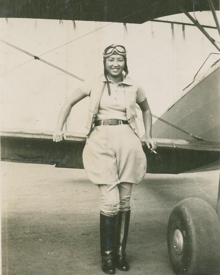 A woman leans against the wing of an aircraft. 