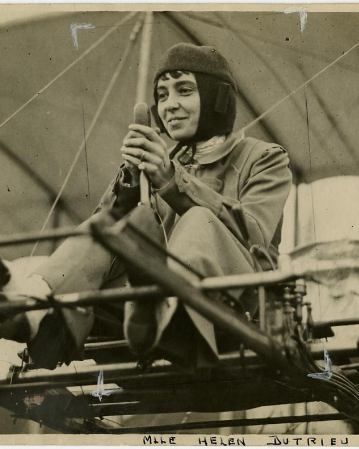 A woman flying a biplane. 