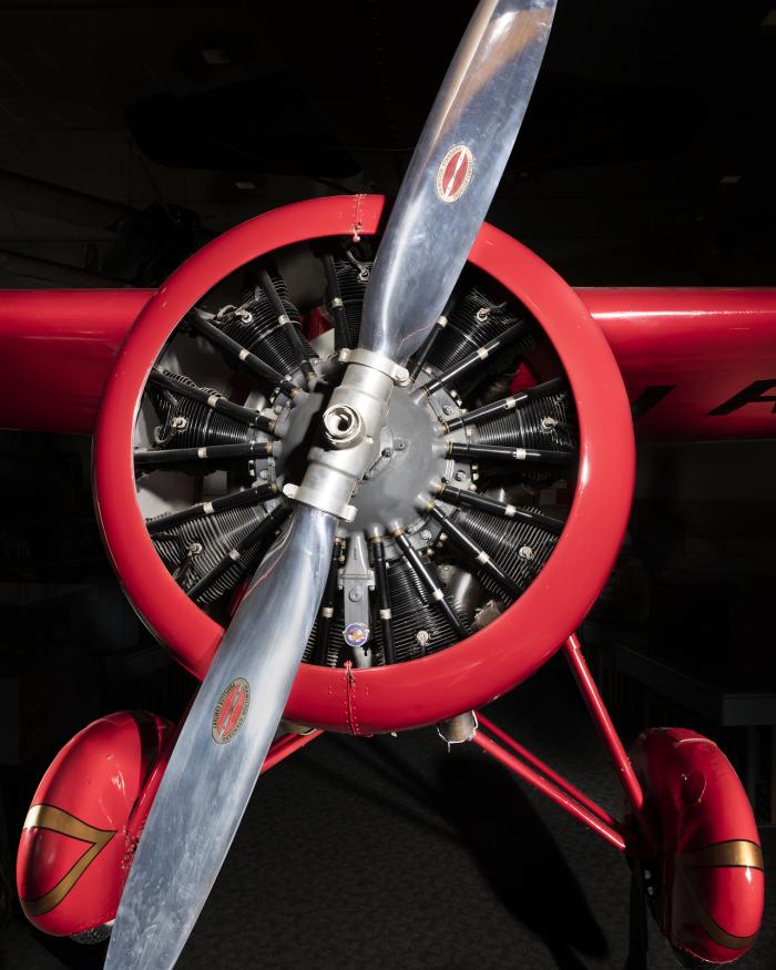 Front engine and silver single-blade propeller on red Amelia Earhart Lockheed Vega 5B aircraft