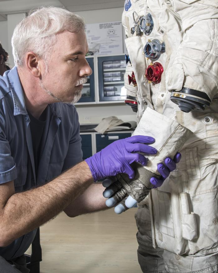 Exhibits Specialist Adam Bradshaw with the white beta cloth lunar spacesuit 