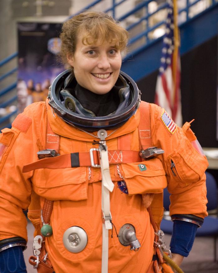 Astronaut Dottie Metcalf-Lindeburger stands in an orange space suit