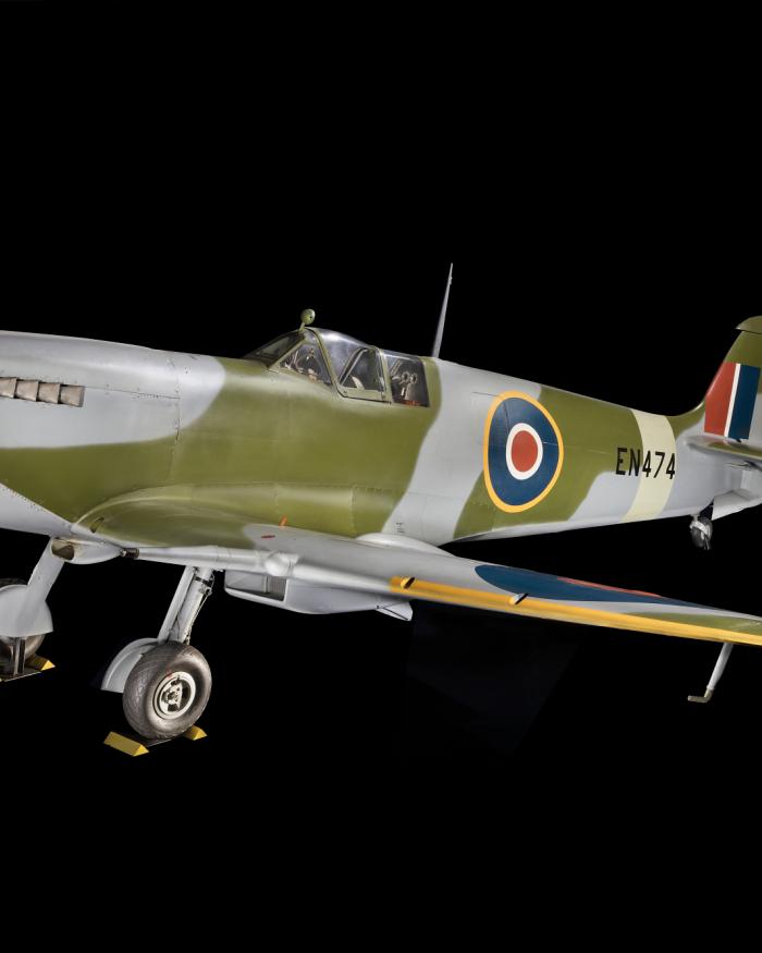 Overall, three-qaurter side view of green and blue Spitfire aircraft