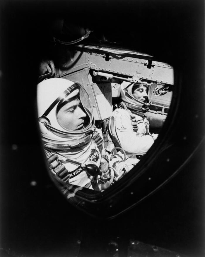 This view of astronauts John W. Young (left), pilot, and Virgil I. Grissom, command pilot, was taken through the window of the open hatch on Young's side of the Gemini-Titan 3 spacecraft just before the hatches were closed in readiness for their three-orb