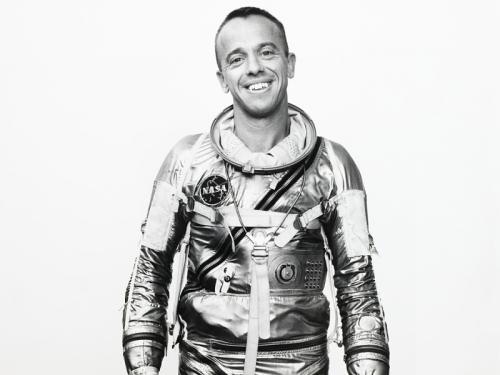 Alan Shepard, in his shiny Mercury spacesuit, smiles at the camera. 