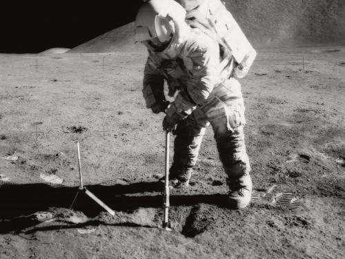 A black and white image of James Irwin digging into the lunar soil during Apollo 15 mission