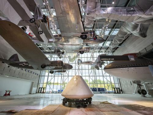 Command module Columbia sits in the middle of a museum gallery and surrounded by exhibits.