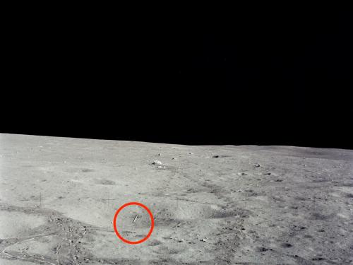 A photo of the surface of the Moon with a red circle around a small circular object, which is a golf ball.