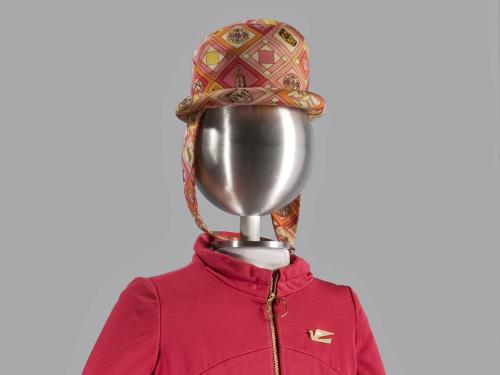 A photograph of a bright pink uniform with matching paisley hat and tights on a mannequin.