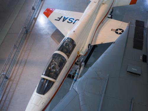 Overhead view of a white and orange painted airplane in the museum hangar.