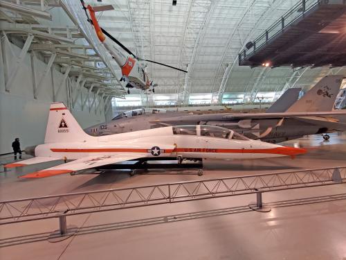 A white T-38 Talon aircraft with orange on the tip of the edges view from a side angle.