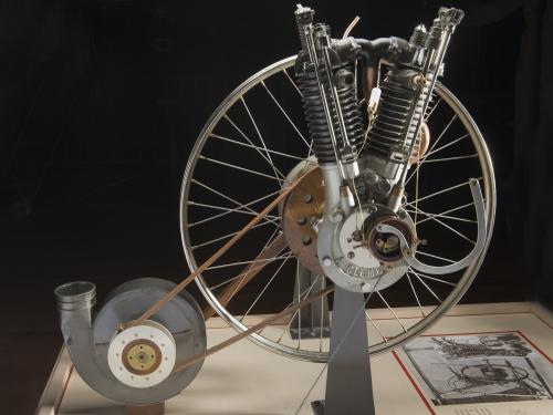 An engine that resembles a bicycle wheel made of metal, wood, and leather.