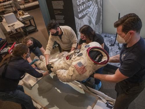 A group of people hold an Apollo spacesuit