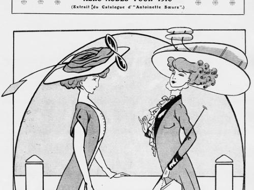 Two women stand facing each other. Both are fashionably dressed in long dresses and large hats. The hat on the right resembles a Wright-type biplane.