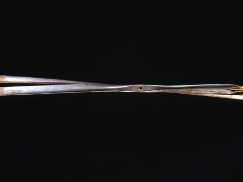 A wooden propeller against a black background. The right side of the propeller is very damaged, and the entire propeller has a split through it.