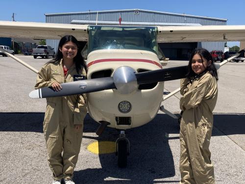 Participants in the S.H.E. Can STEAM Aviation Camp pose in front of an airplane