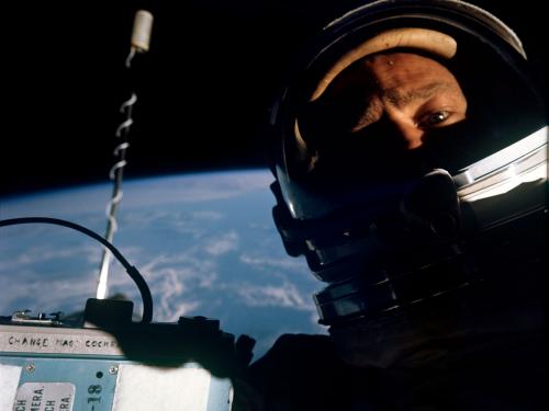 Man in spacesuit photographed from the chest up with the blue of Earth behind him