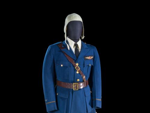 A uniform on a mannequin which includes a deep blue jacket, beige flying hat, beige pants, and tall brown boots.