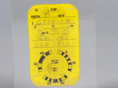 A small rectangular yellow card incased between two pieces of clear plastic. The area at the top of the card denoting the pilot name is marked with a B, presumably for Frank Borman. The rest of the card has different numbers recorded related to different optical measurements.