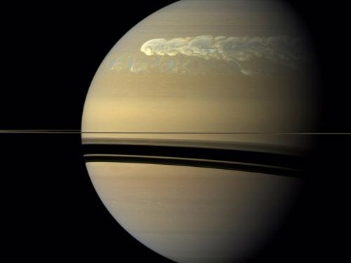 A view of Saturn with a strip of swirling clouds running across the top.