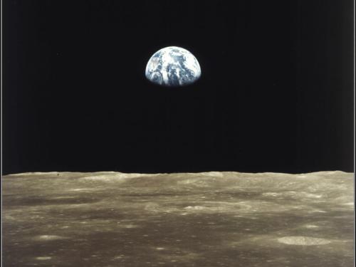 An image taken from the surface of the Moon looking toward Earth. The bottom one-fourth of the Earth is shrouded in darkness.