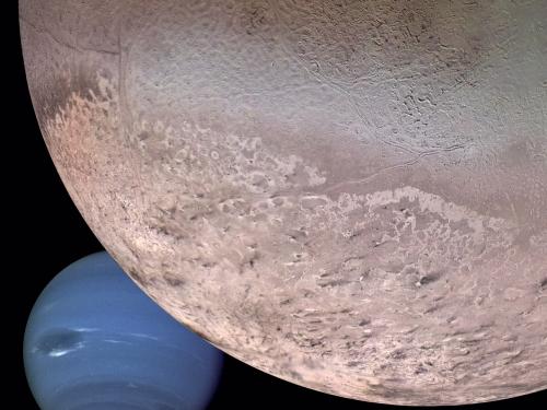 Triton takes up the top right corner of the frame, extending almost its entirety. Neptune can be seen behind Triton in the bottom left.