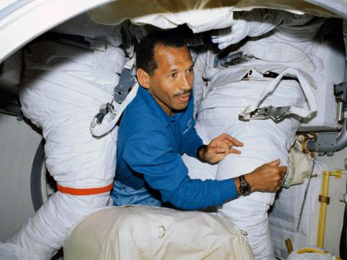 A man floats through two space suits aboard the Space Shuttle.