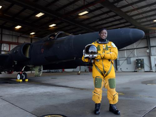 A black woman wearing a pressure suit stands in front of a Lockheed U-2.