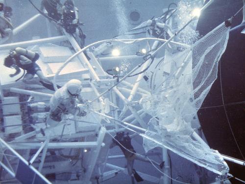 Astronauts and divers underwater working on a space simulator