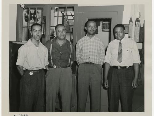 Four men stand inside an industrial building