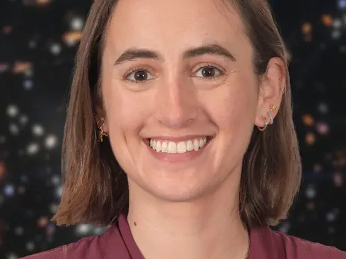 Portrait of a woman. She is smiling and wearing a burgundy shirt. Behind her is a star field.