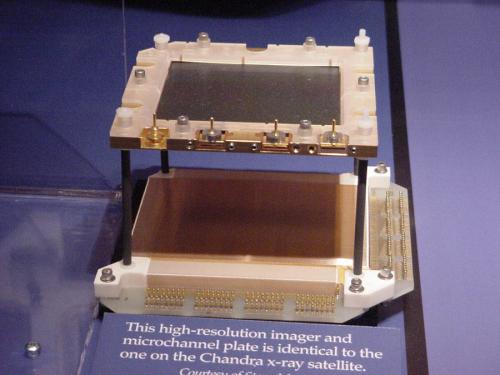 Two metal and plastic plates attached to each other by rods at each of the plates four corners, suspending the top plate above the bottom one. The bottom plate is much thicker than the top.