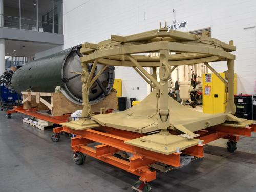 Center section of V2 rocket is attached to a launch table in a restoration facility.