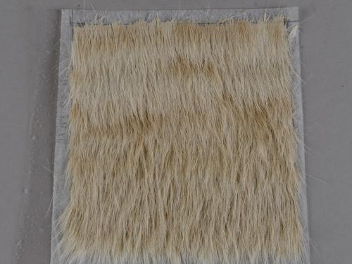 A sample of cow hair adhered to a spun-bond polyester substrate.