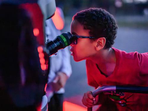 A young visitor looks through a telescope eyepiece