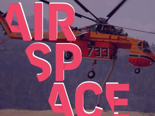 An orange helicopter sucks water up in a tube, while hovering in the air. The AirSpace logo is superimposed over top.