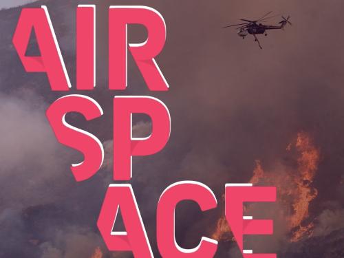 A helicopter dispatches water on a raging wildfire. The AirSpace logo is superimposed over top. 