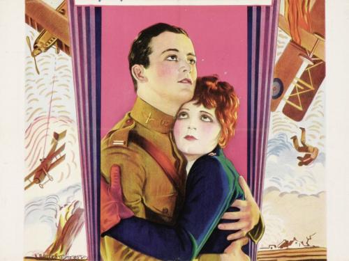 A colorful poster for the movie Wings shows a man in a WW1 uniform and a woman embracing with planes on either side. 