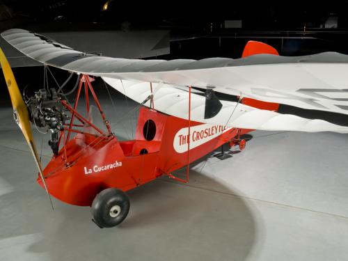 Wing of a red and white open-cockpit staggered wing aircraft 