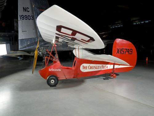 Wing and propellers of a red and white open-cockpit staggered wing aircraft 