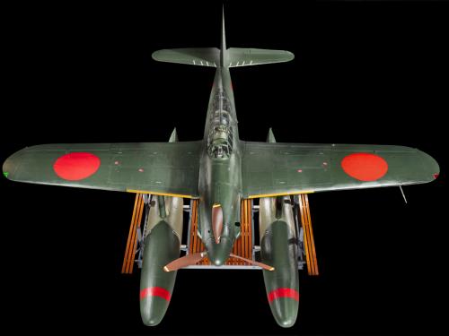 Above view of a green bomber with red roundels on the wings and twin floats in place of wheels.