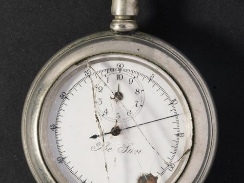 Broken stopwatch with hand pointed at nine-minute mark. 