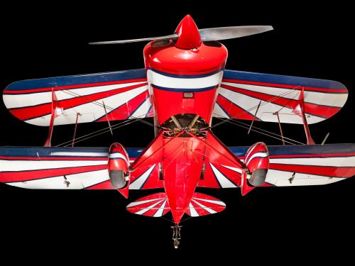 View of the landing gear of a red, white, and blue painted aerobatic biplane. 