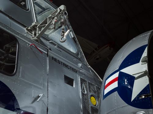 View of a cargo hook and a nose of a helicopter. The nose is open and painted on is the United States Air Force insignia.