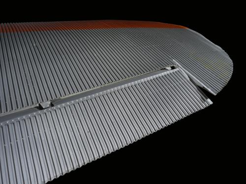 Close up view of a silver and orange painted wing of an airplane.