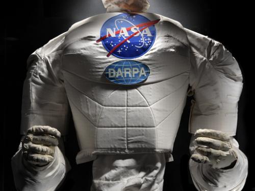 Frontal view of a body of a robot with arms, chest with a NASA logo, and an orange face cover.