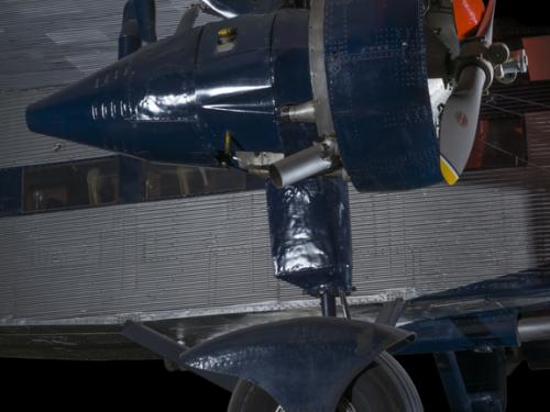 Blue painted engine of an airplane. In the background of the image is an aircraft. 