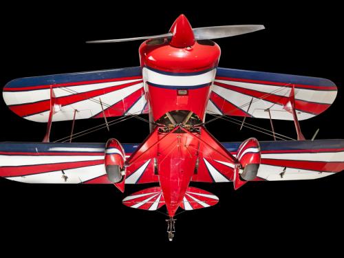 View of the landing gear of a red, white, and blue painted aerobatic biplane. 